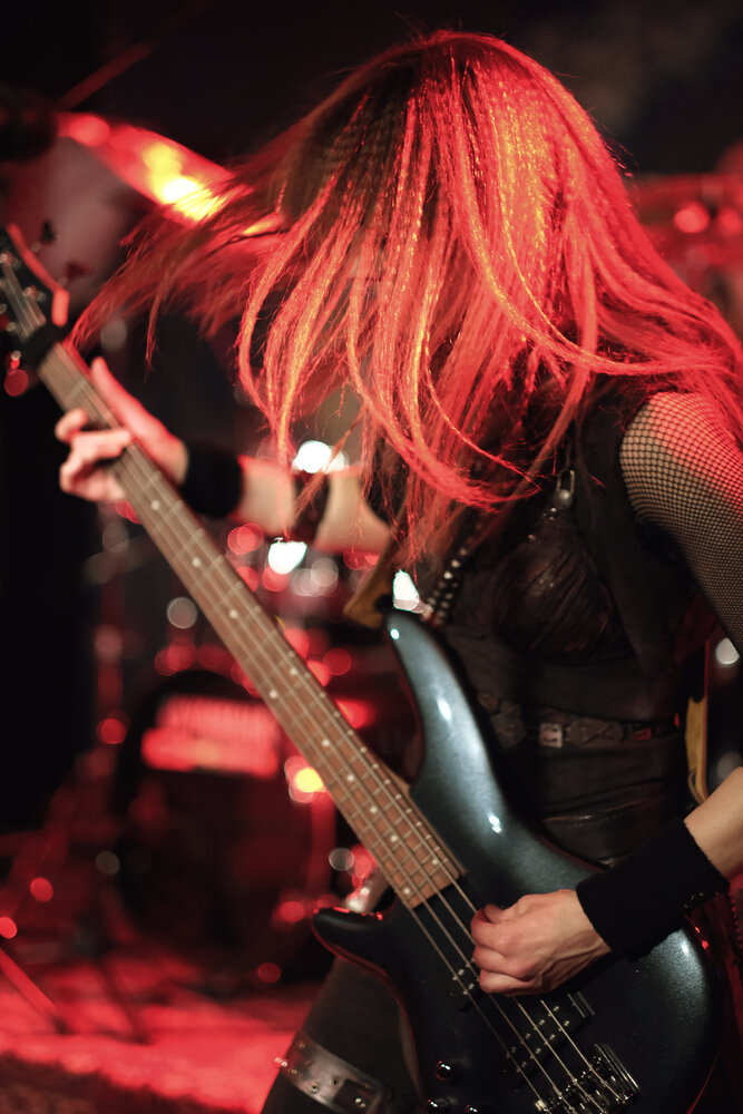 Left-hand bass player with long hair covering their face.