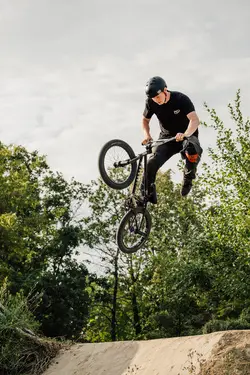 A BMX rider up in the air. Their hands are touching the handlebars, their legs are away from the pedals.