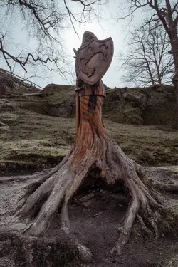 An undead knight with a sword and a shield carved out of a tree stump.