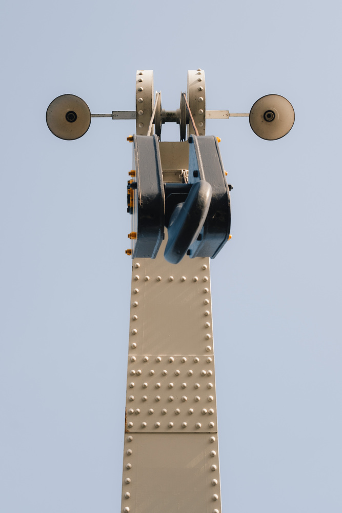 A crane viewed from below. Two lamps on the sides look like eyes, the main hook block looks like a nose. The structure resembles a mantis.